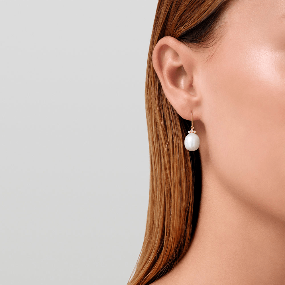 Model bærer Lovina Earrings i 14 karat guld med hvid ferskvandsperle, tæt på øret