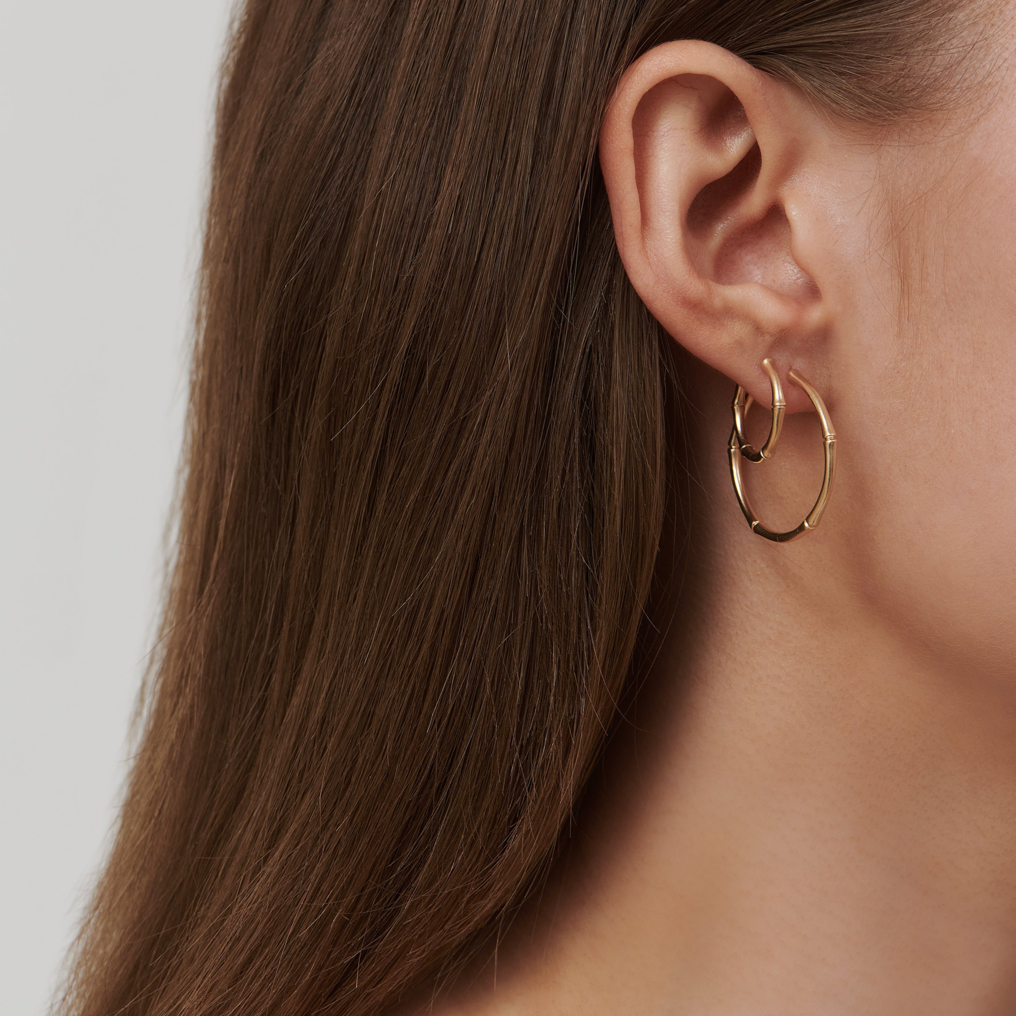 Model iført flere Bamboo Hoops i 14K guld, lagdelt i øret