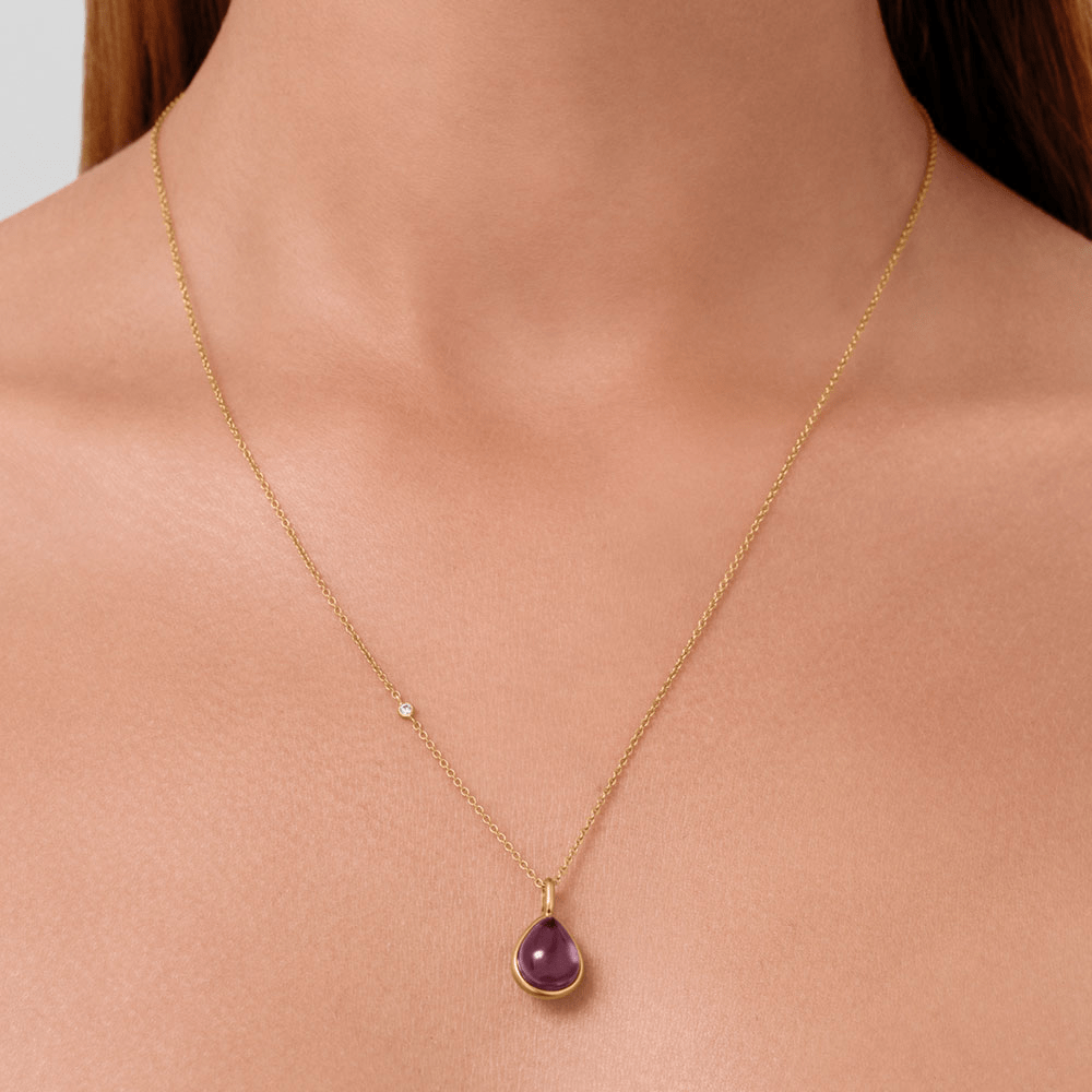 Paloma vedhæng med lilla krystal båret om halsen på tynd guldkæde