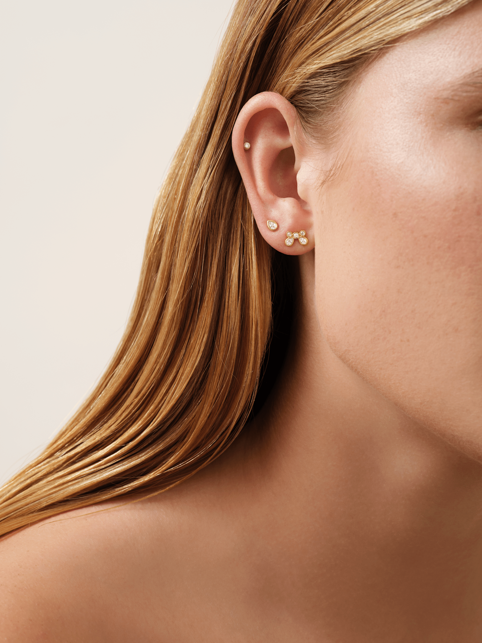 Model bærer White Wisteria Drop Earstud nederst i øret, stylet sammen med en cartilage-stud og en tre-stens ørestik