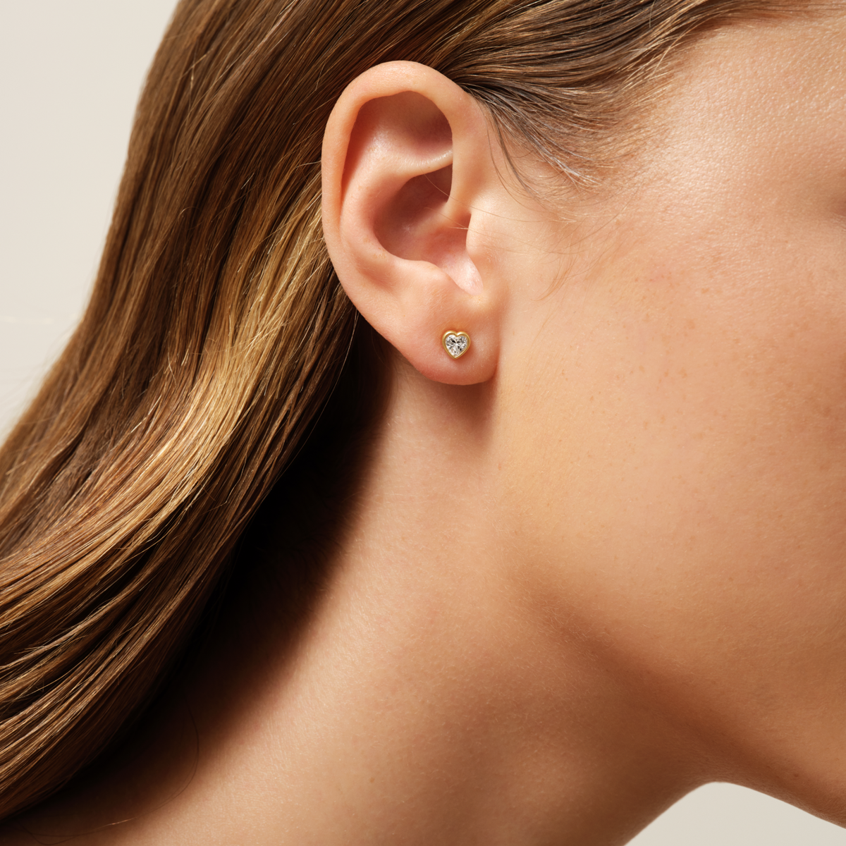 Model bærer Amorina ørestik med hjerteformet cubic zirconia på øret
