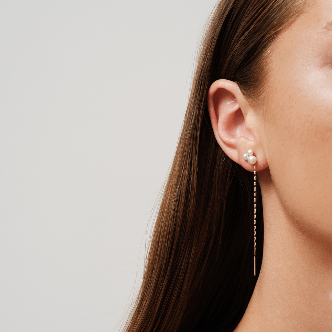 Model bærer Esther Look øreringe i guld med perleklynge og lang kæde ved øret