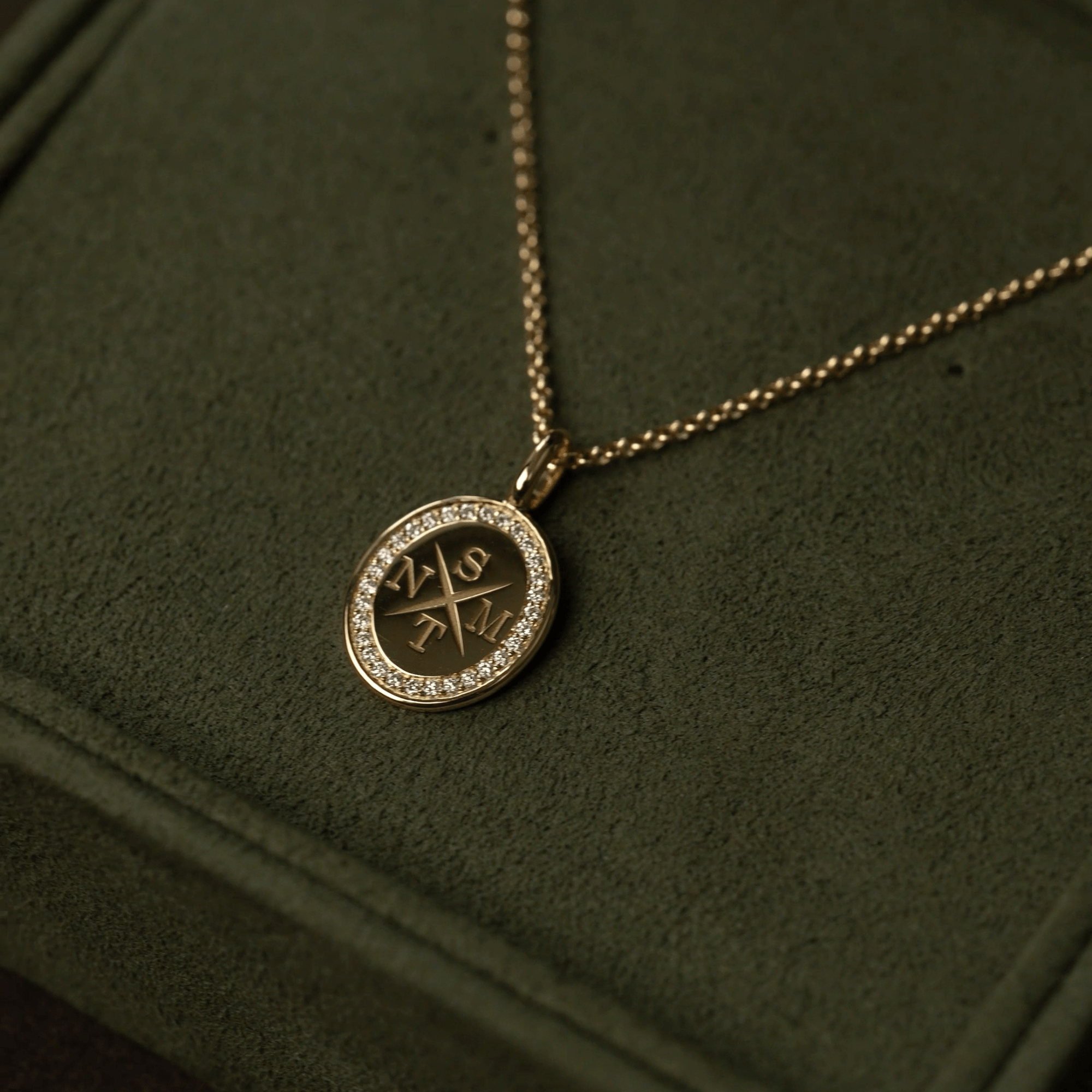 Medallion halskæde i 18K guld med diamantkant og indgraveringen NSTM, close-up