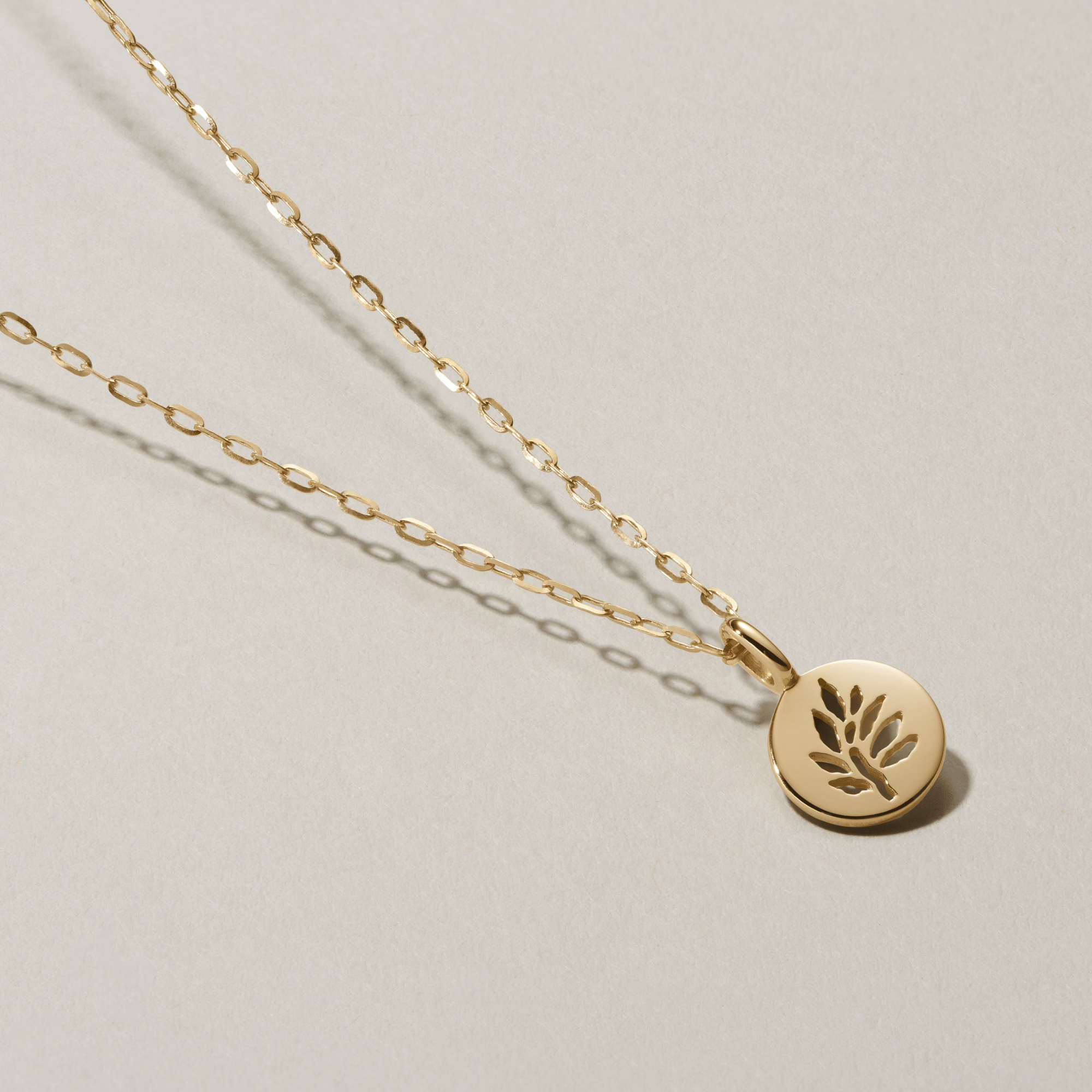 Legacy Pendant i guld på kæde, fotograferet som flatlay