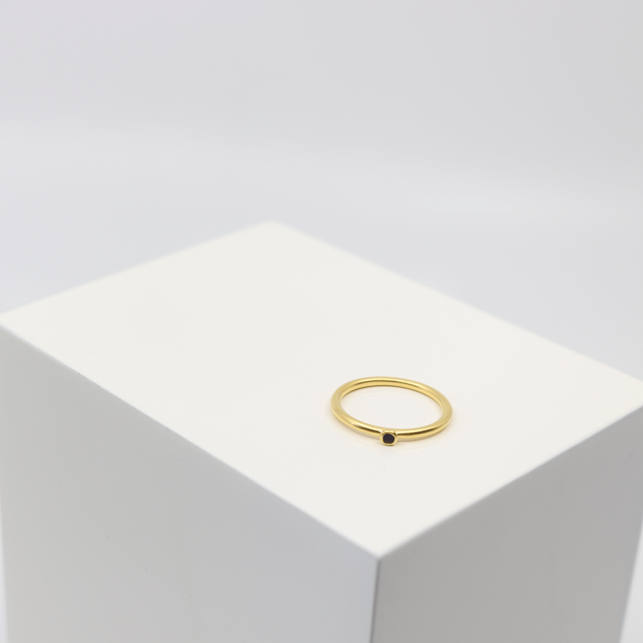 Finesse Ring i forgyldt sølv med mørk sten, foto på kant