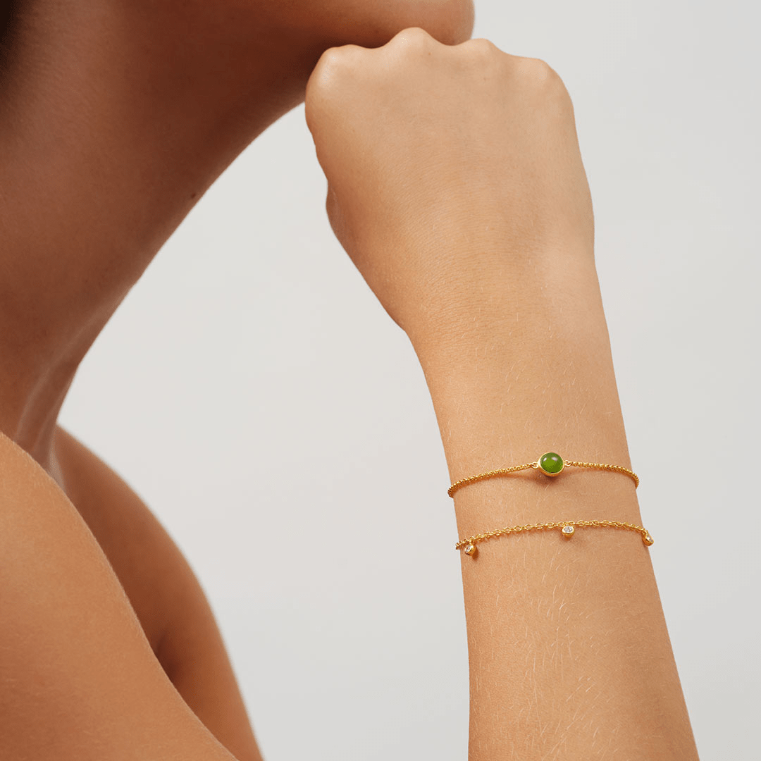 Model bærer Primini and Grace Bracelet Look på håndleddet - to lagdelte armbånd med grøn sten