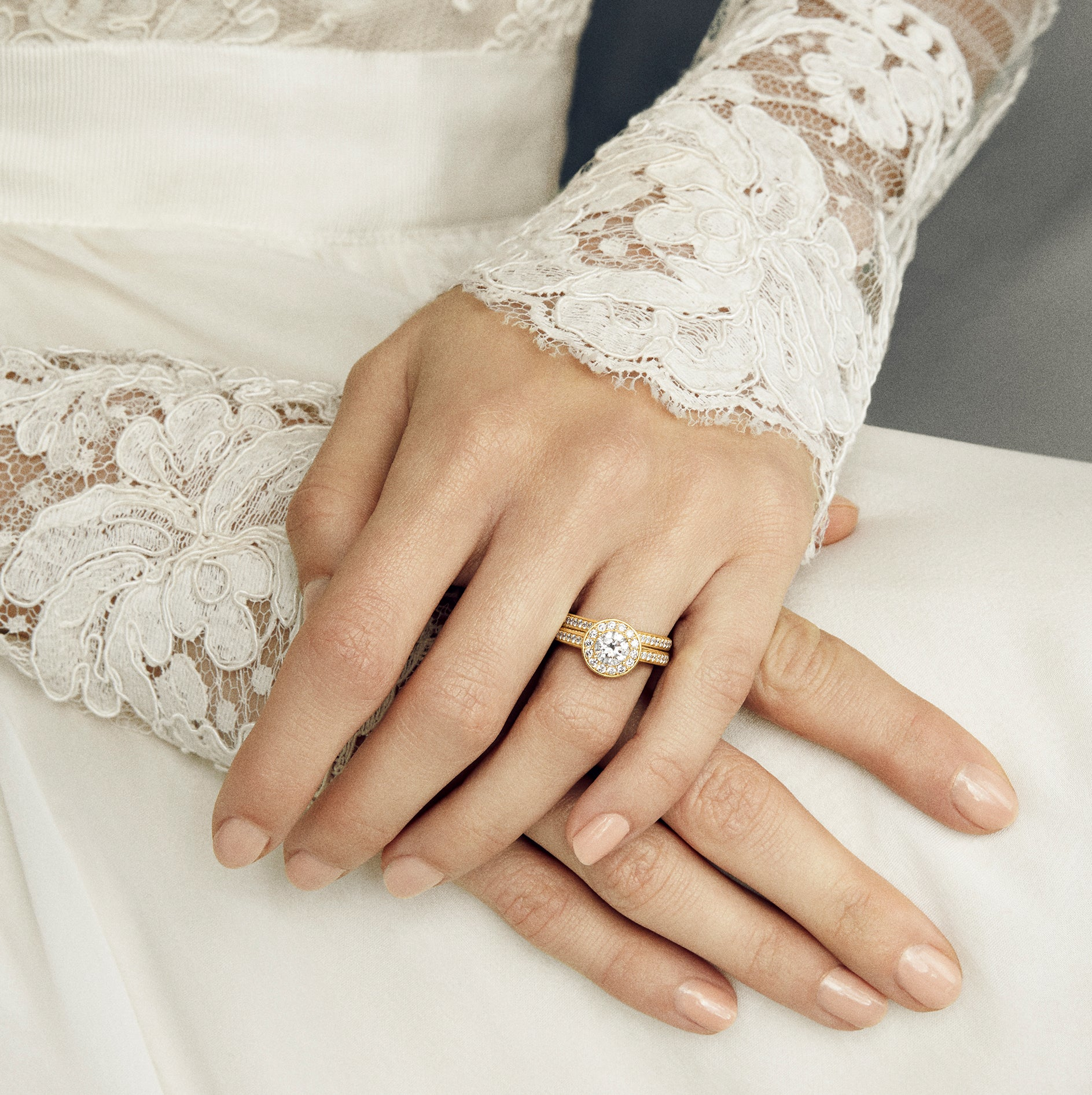 Model i brudekjole med blondeærme bærer Eternity Diamond forlovelsesringen fra Julie Sandlau stacket med en vielsesring.