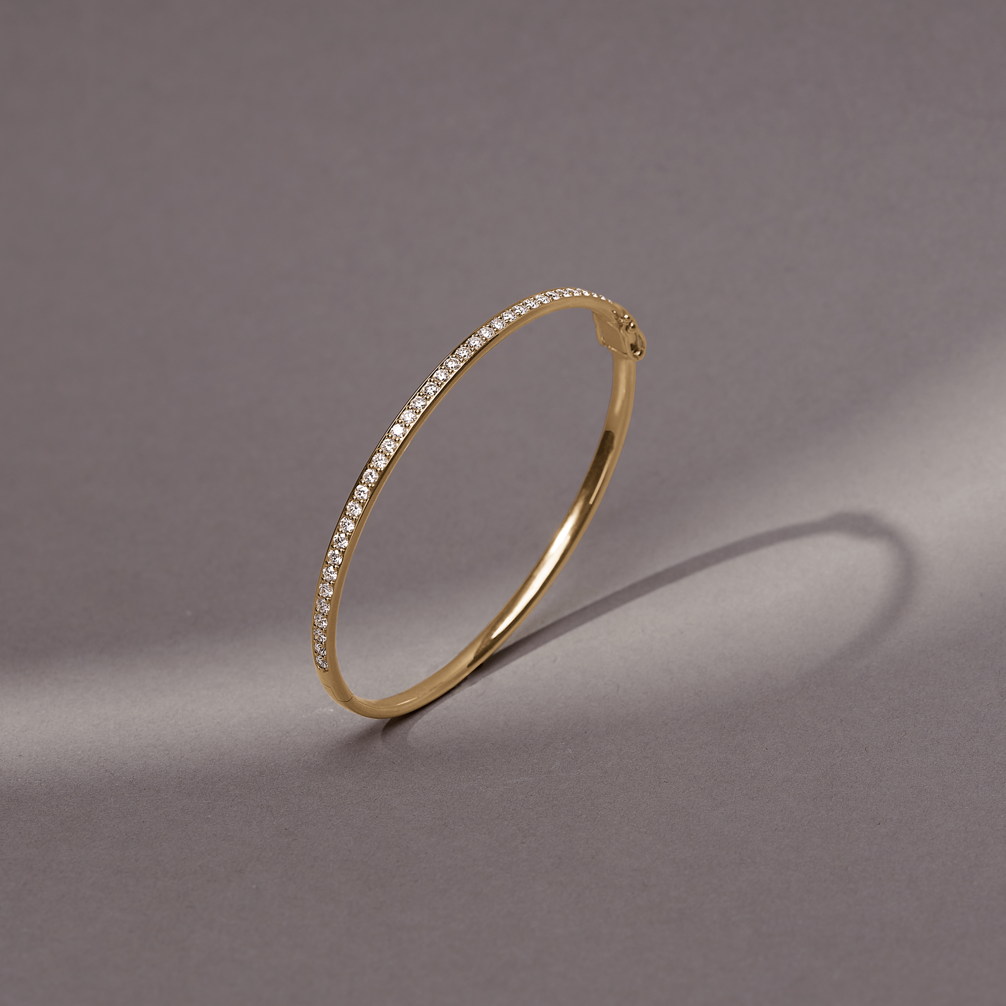 Elegance Armbånd i 18K guld med diamanter, close-up på grå baggrund.