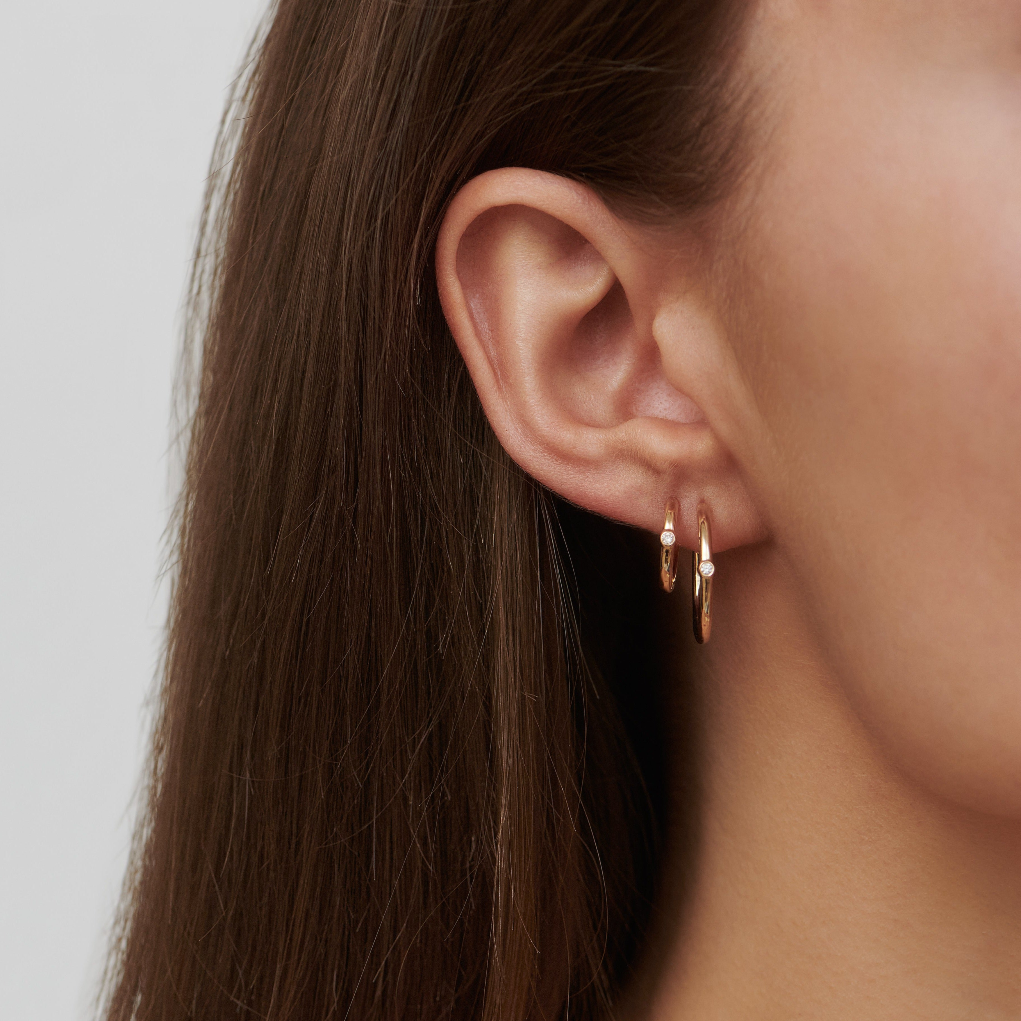 Model bærer to Purity Medium Hoop creoler med diamant i ørerne