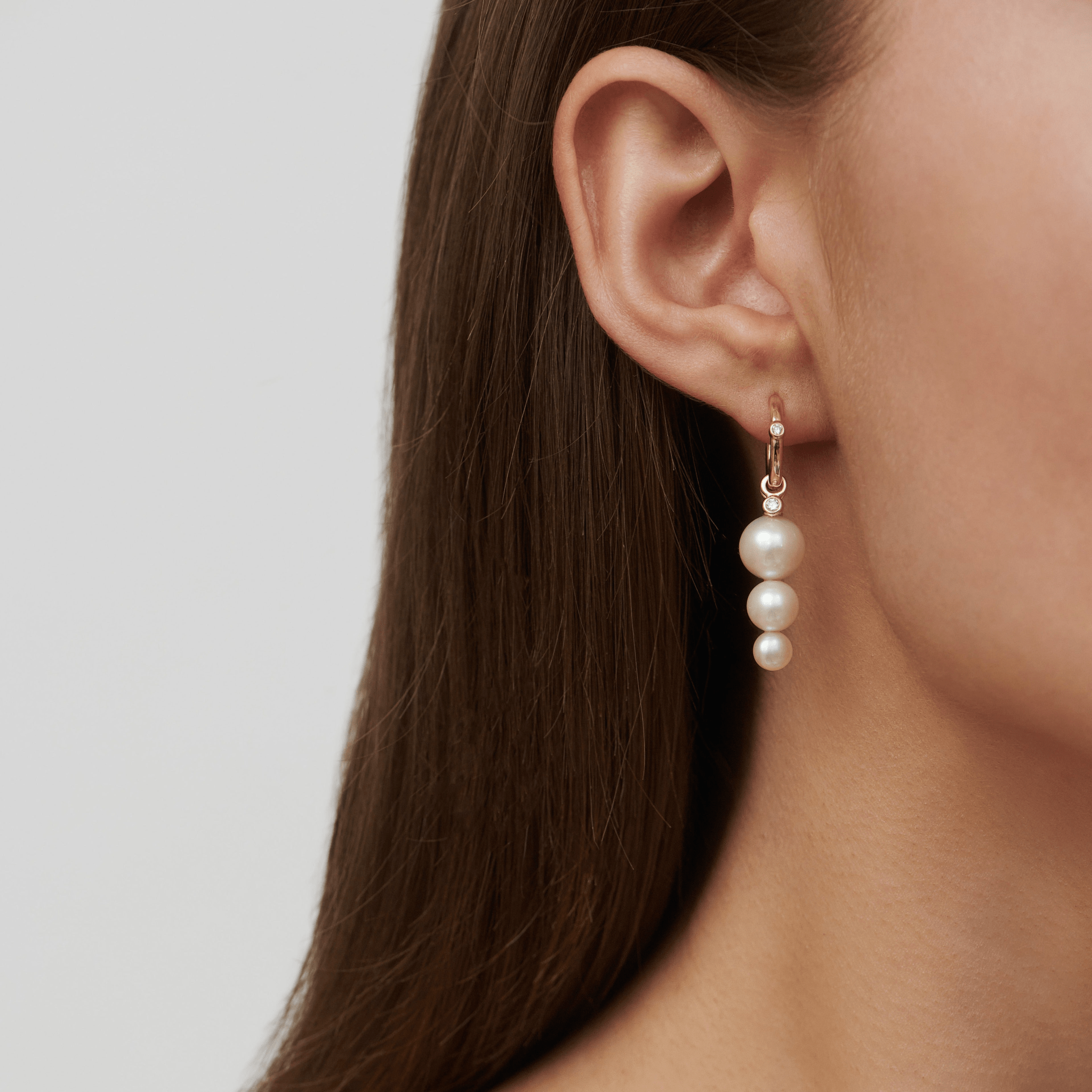 Model bærer Purity Medium Hoop i øret, stylet med et flerlags perle ear pendant