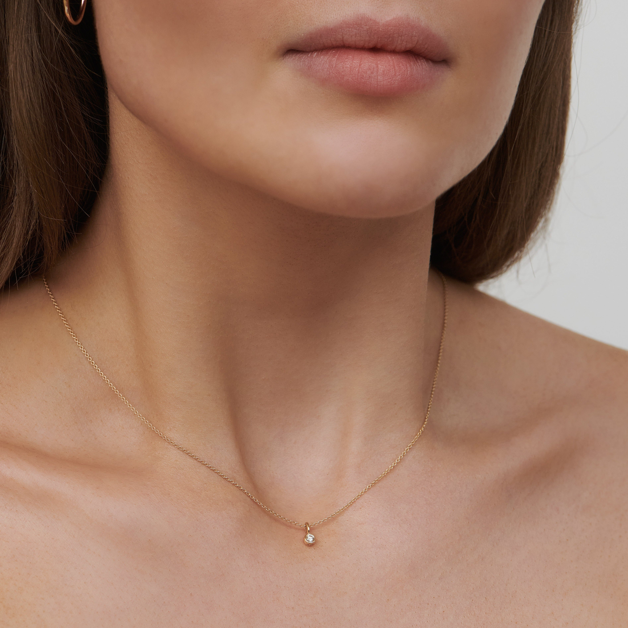Model bærer Purity vedhæng i 14K guld med diamant om halsen