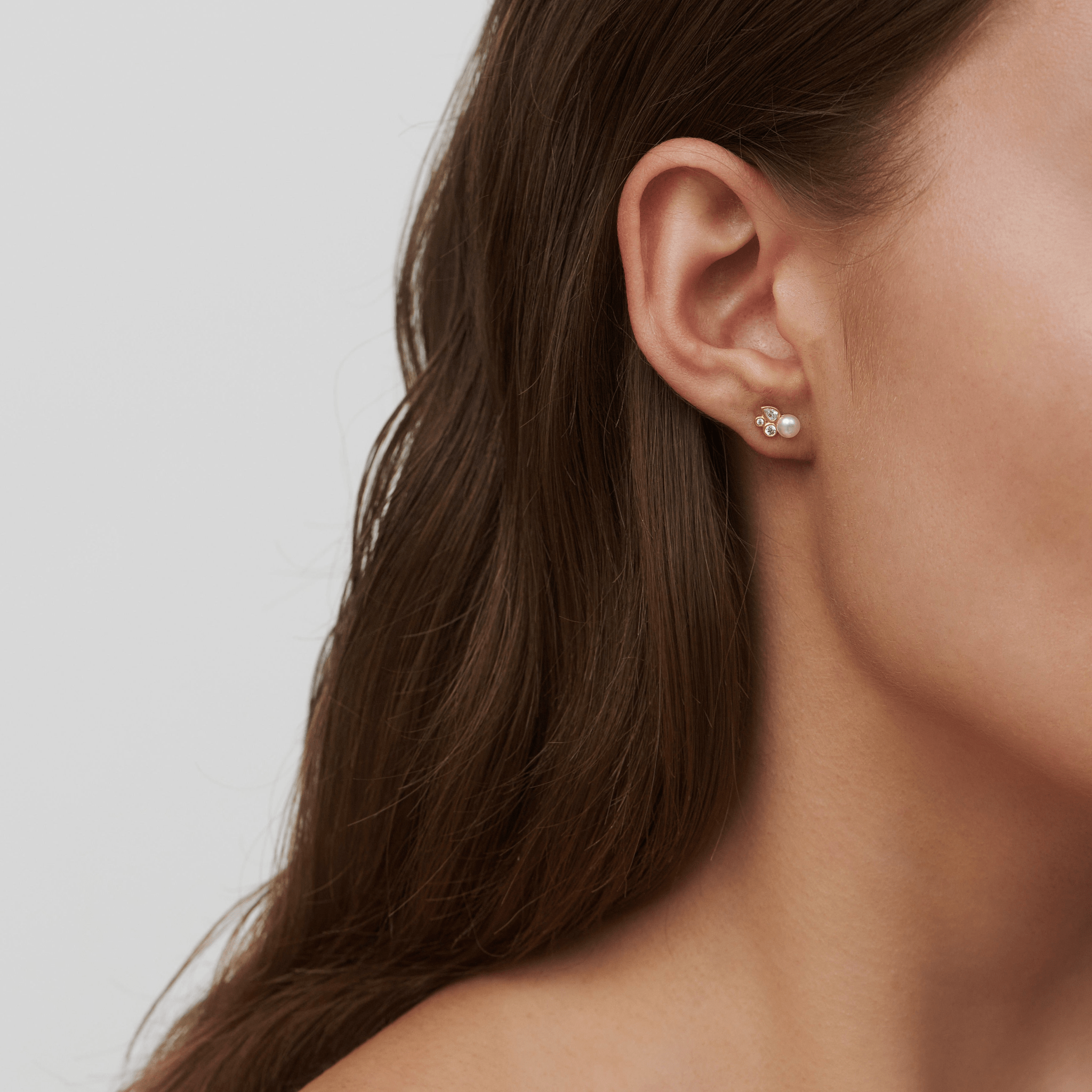 Tasha ørestikker i guld med perle og zirkonia båret i øret, close-up