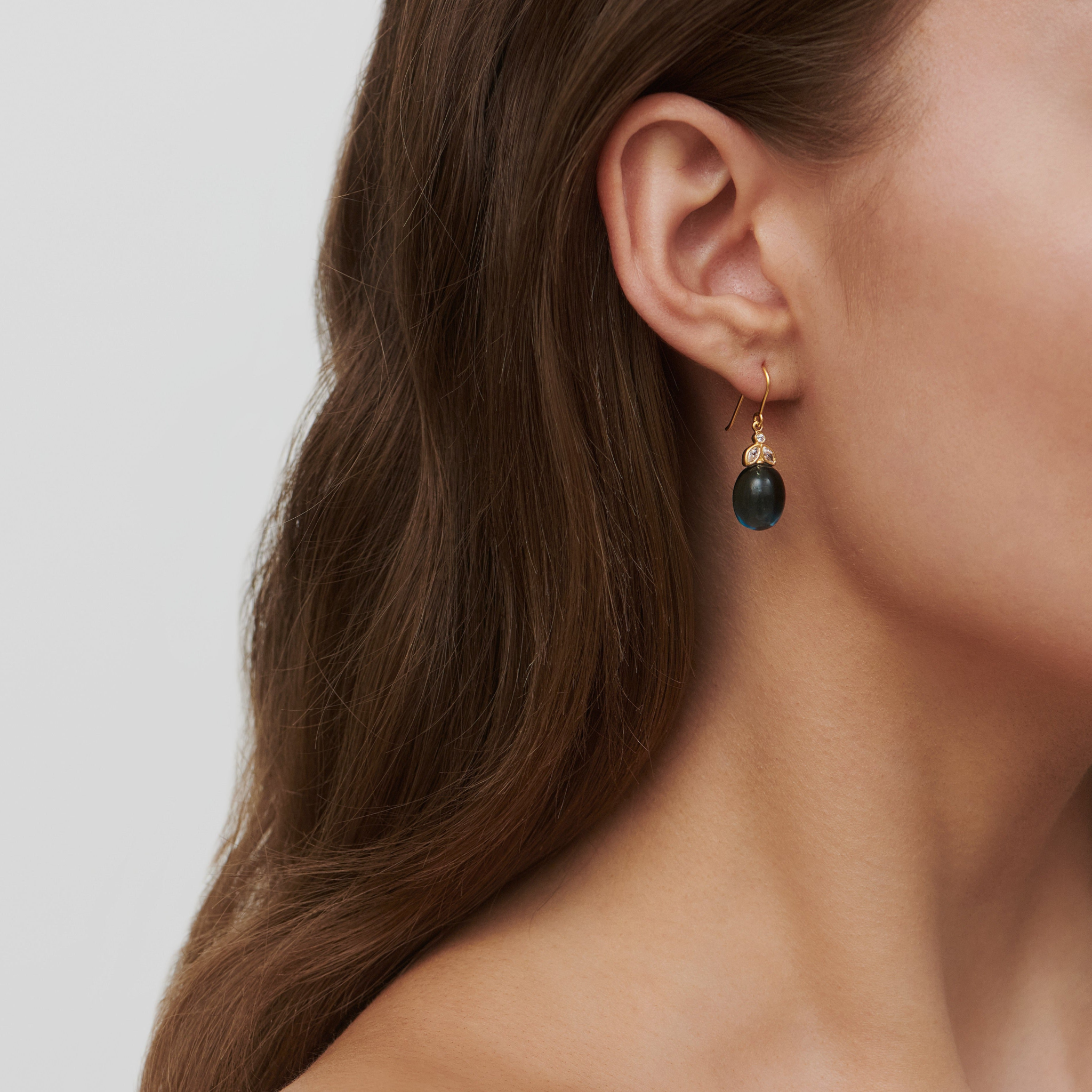 Model bærer Tasha ørering i forgyldt sølv med brun sten, close-up på øret