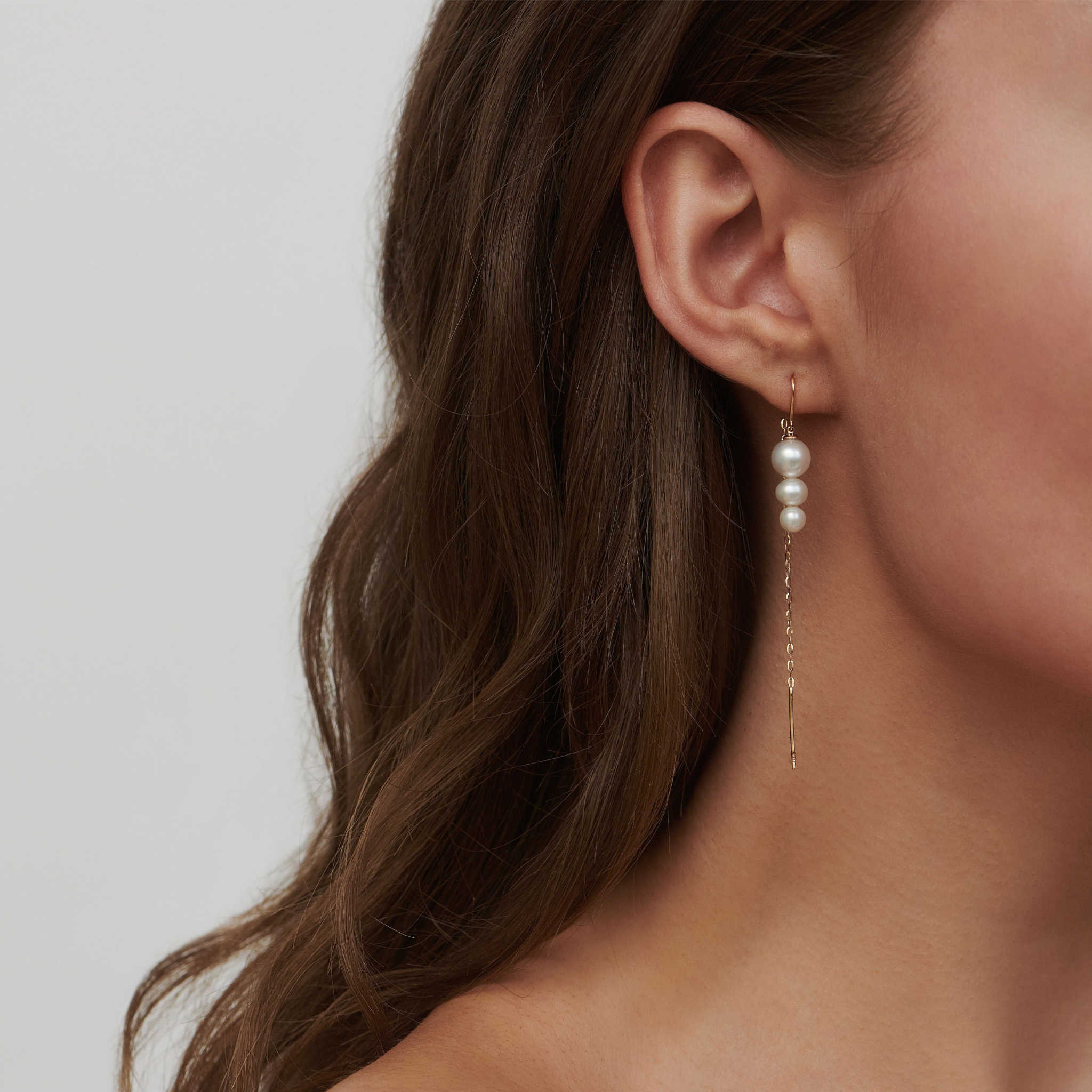 Model bærer Eden Chain Earring med ferskvandsperler og lang guldkæde, set fra siden