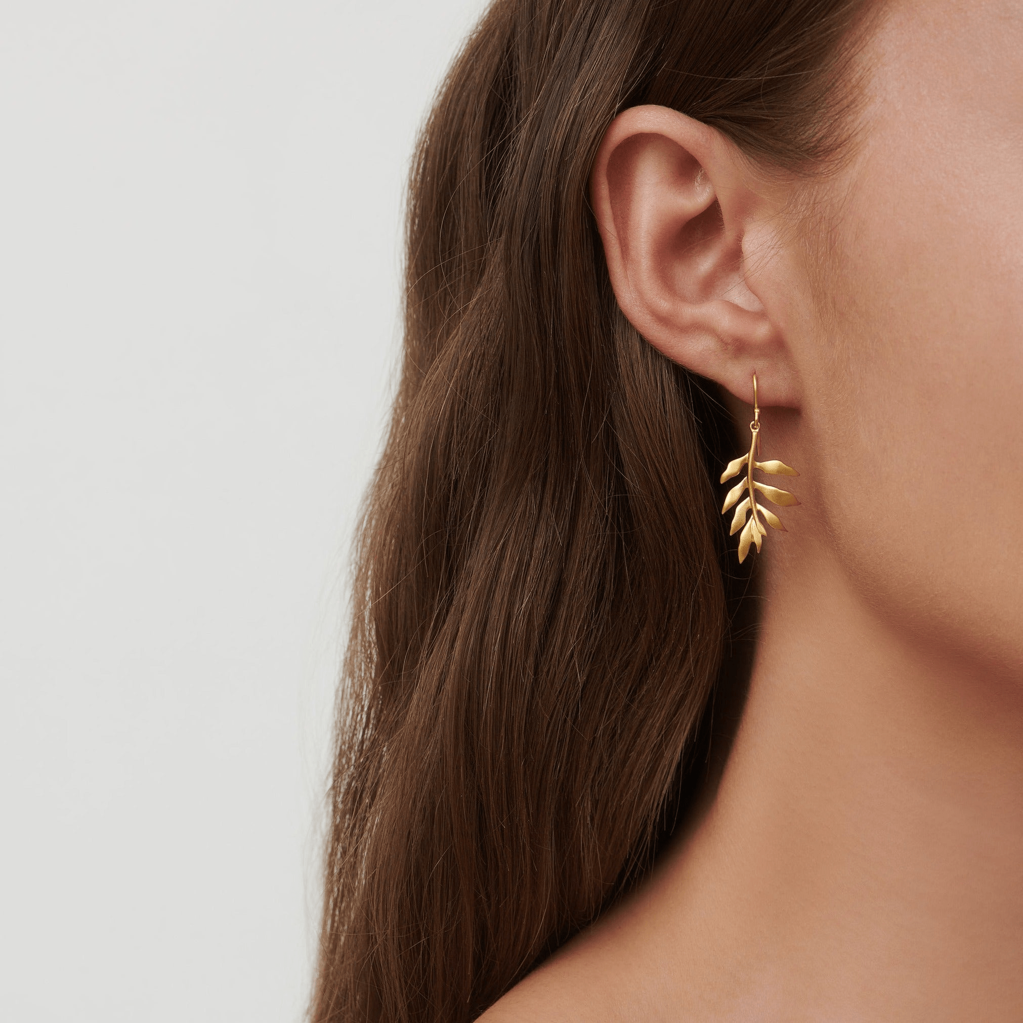Model bærer Tree Of Life Earrings med logo-vedhæng i øret