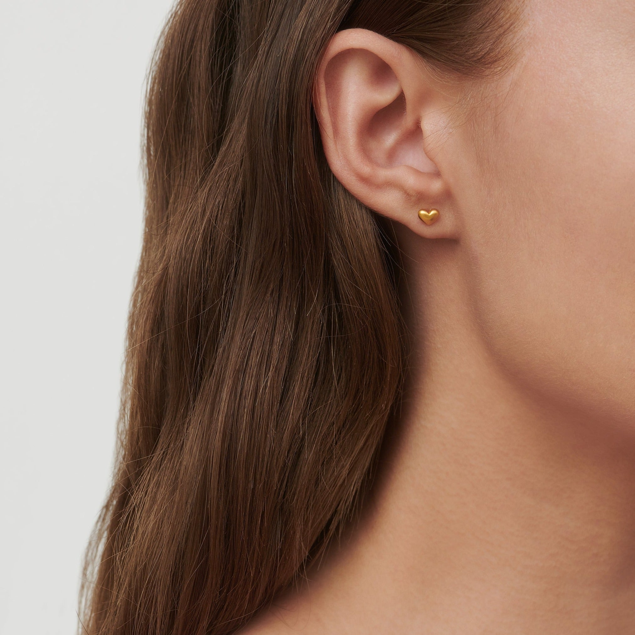 Love ørestikkere i guld båret i øret, close-up på model