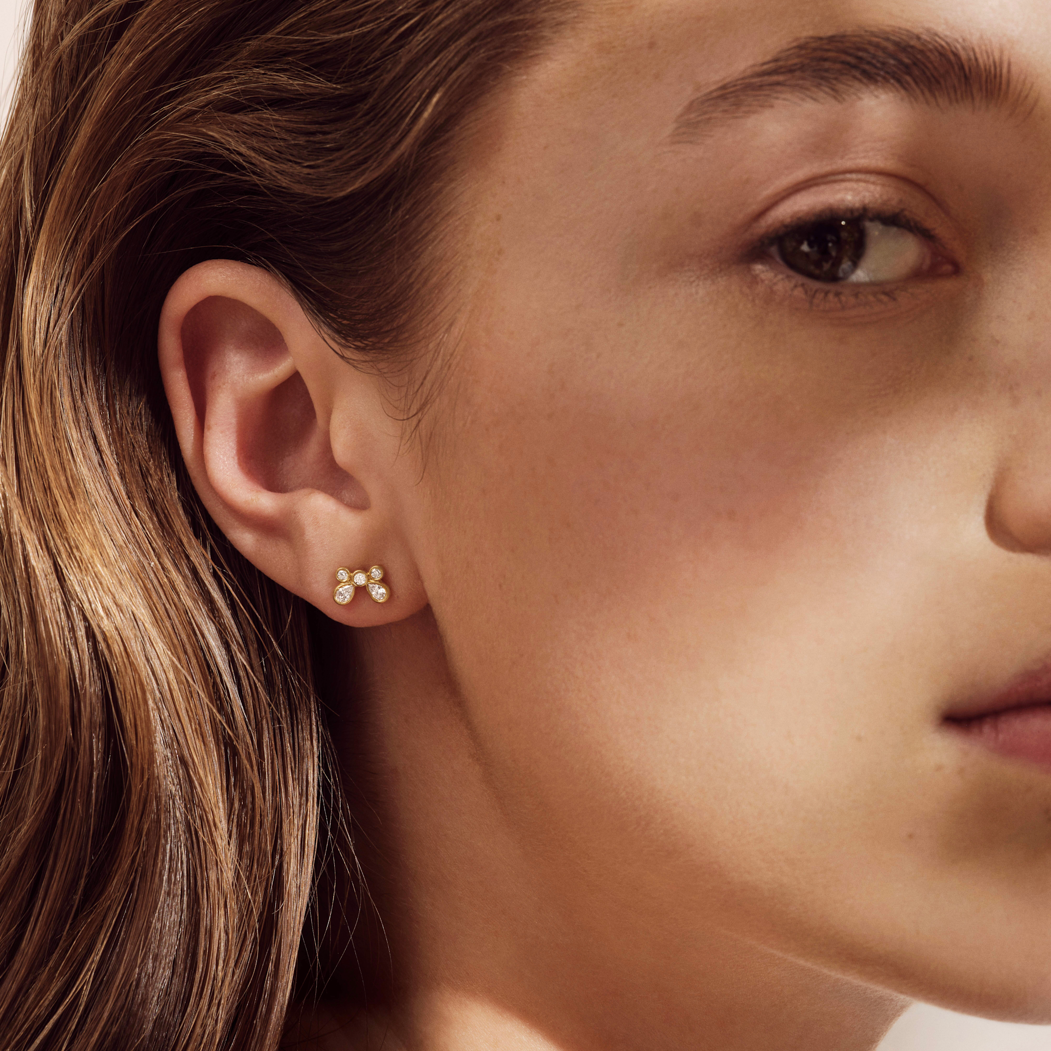 Model bærer Meadow Earstud i forgyldt sølv med cubic zirkonia, tæt på øret.