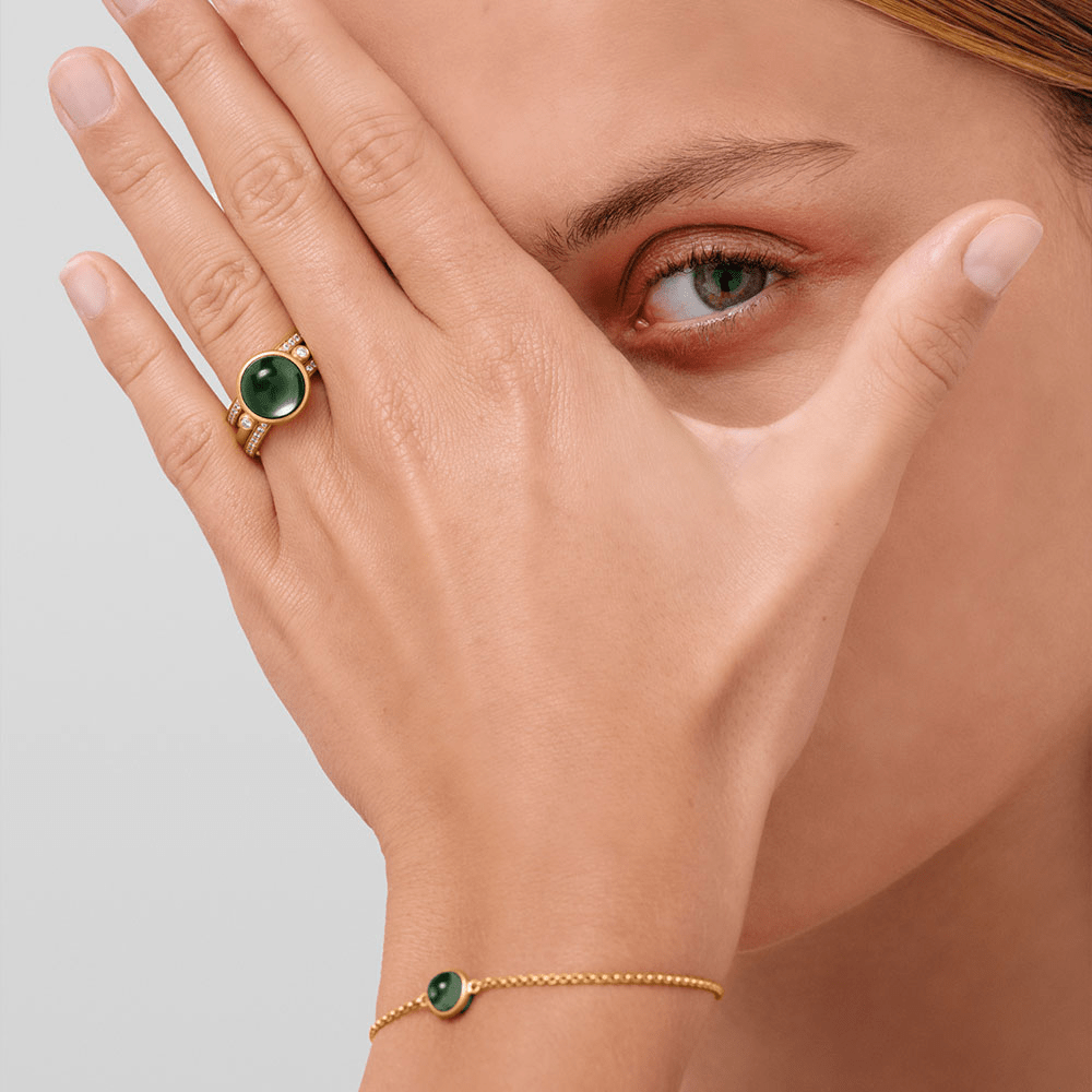 Prime Ring i sandblæst guld med grøn krystal, båret på hånd sammen med matchende armbånd