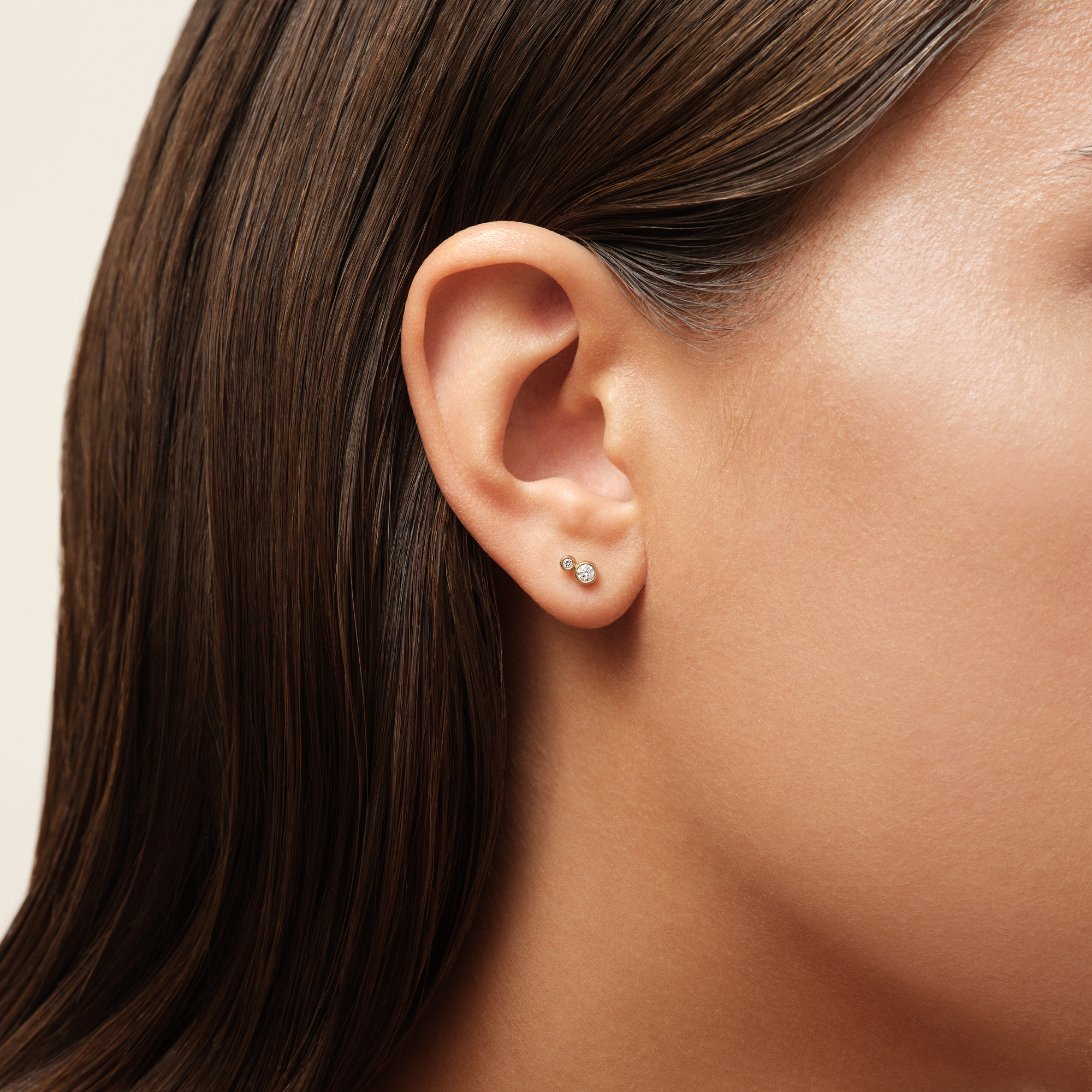 Model bærer Fina ørestikker i 18K guld med diamanter, close-up på øret