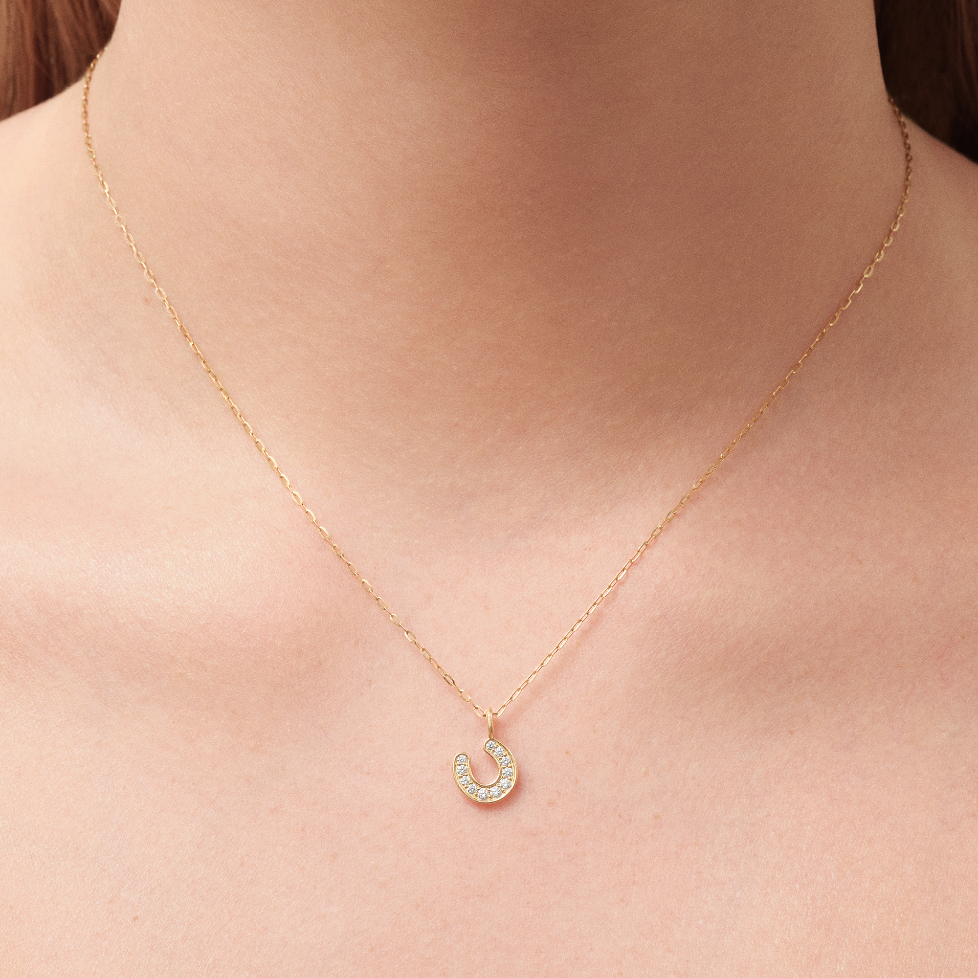 Model bærer Horseshoe Pendant i 14K guld på tynd guldkæde