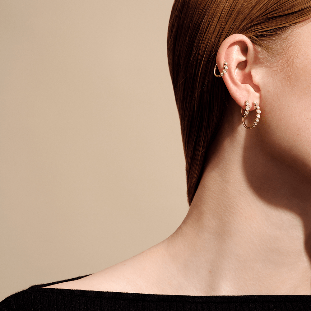 Model bærer lagdelte hoops, heriblandt en diamantbesat hoop