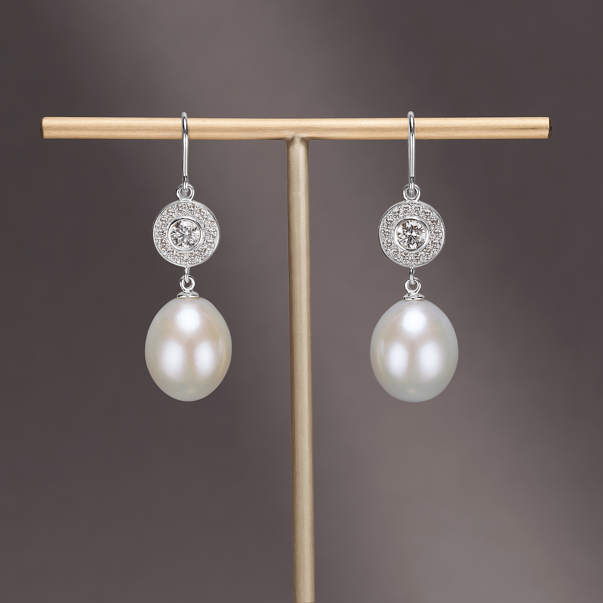 Heritage Earrings i 18 kt hvidguld med diamant-halo og aftagelig perledråbe, still-foto på smykkestativ