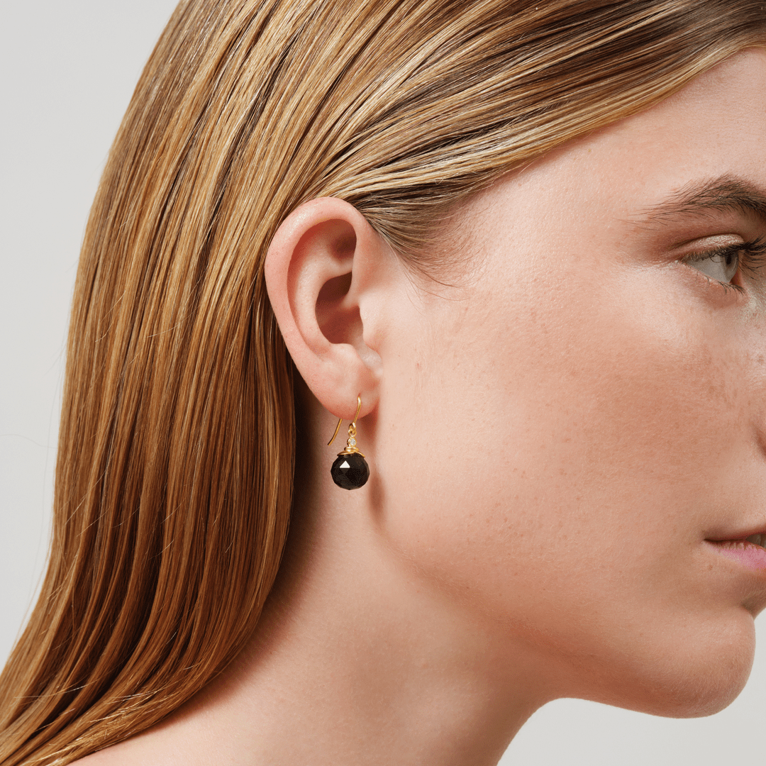 Model bærer Berry Earrings med mørk facetteret krystal i forgyldt sølv