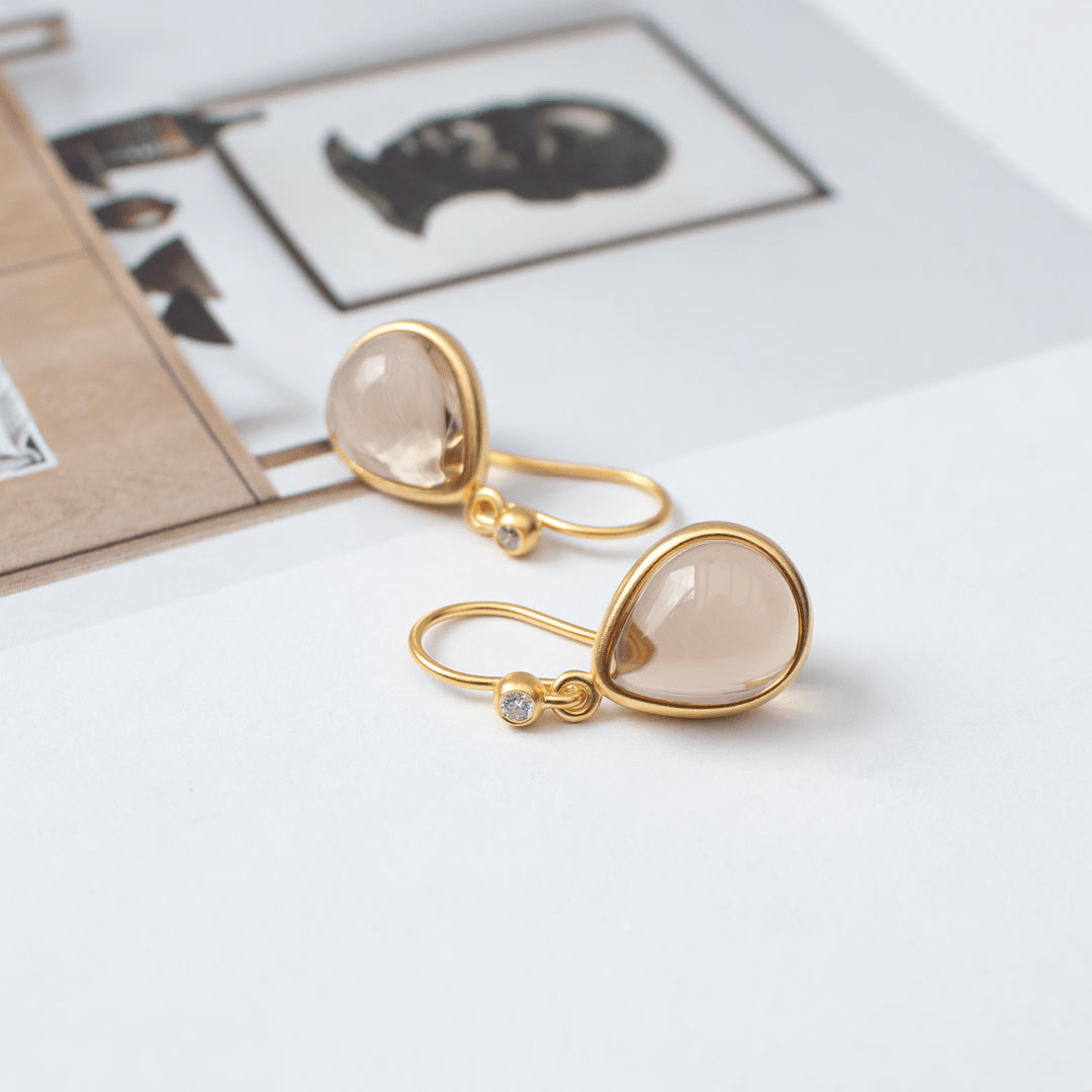 Paloma øreringe i forgyldt sølv med beige pear cabochon-krystal, stylet på magasin