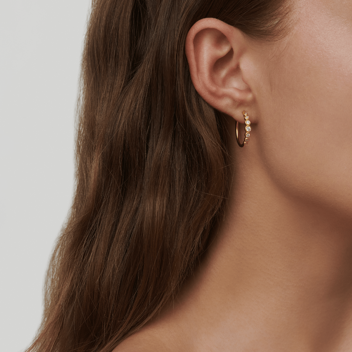Model bærer Grace Hoops creoler i forgyldt sølv med zirkoner, close-up på øret