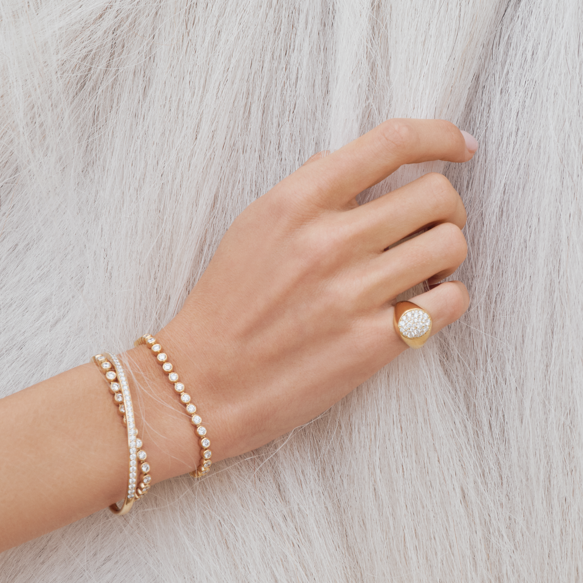 Model bærer Multipave signetringen fra Julie Sandlau på fingeren sammen med guldarmbånd besat med diamanter.