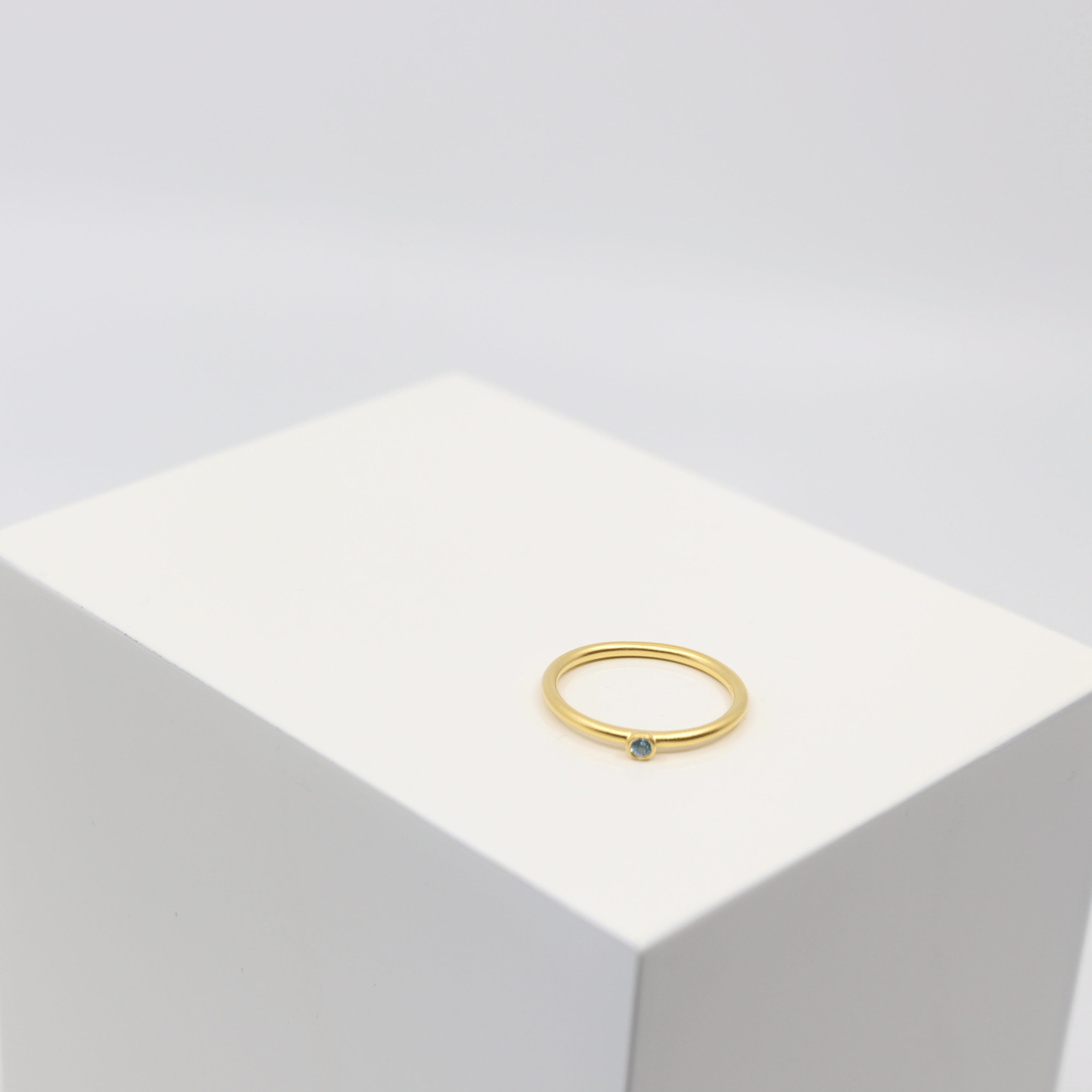 Finesse Ring i forgyldt sølv med lyseblå sten, foto på kant