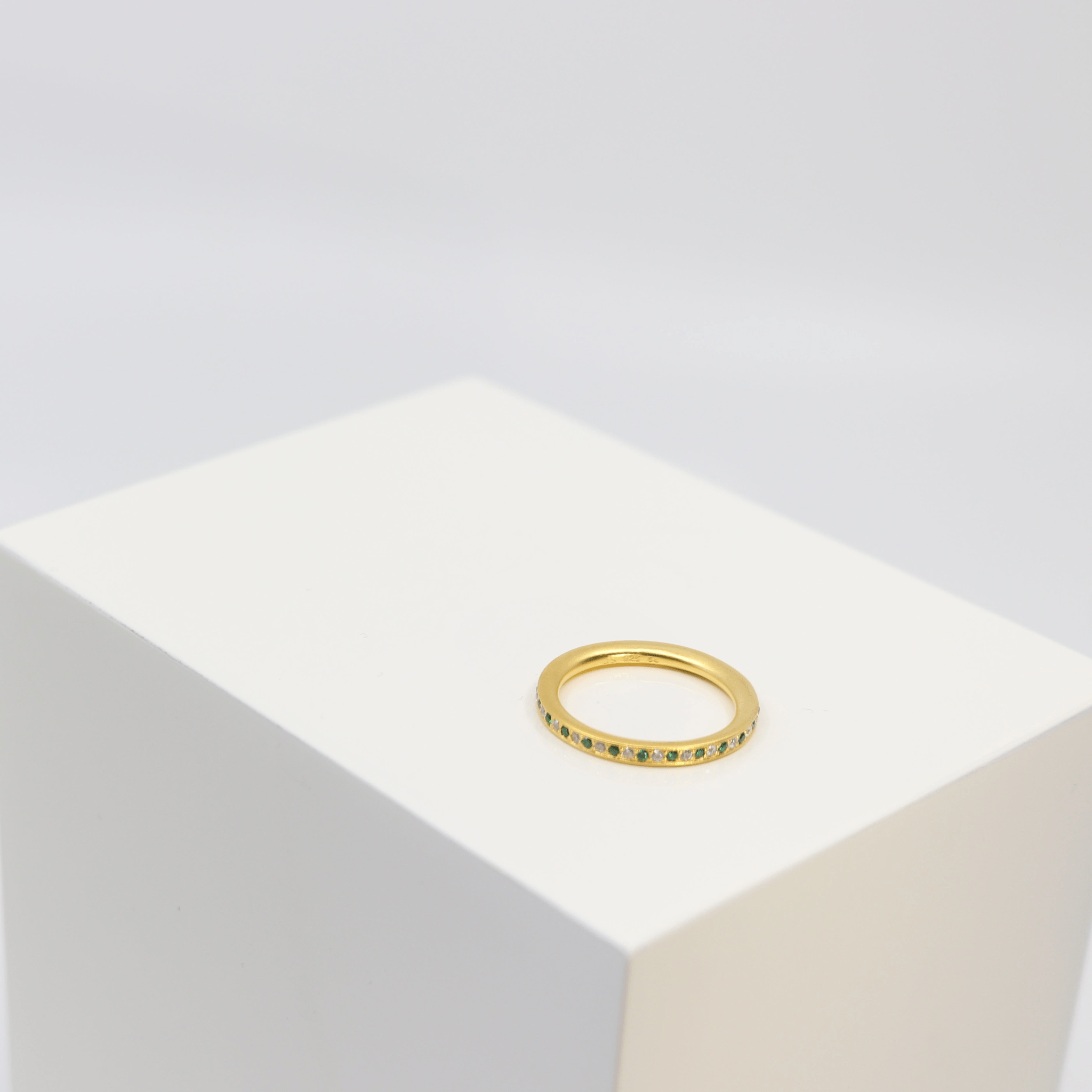 Infinity Ring i forgyldt sølv med grønne zirkonia sten, foto på kant