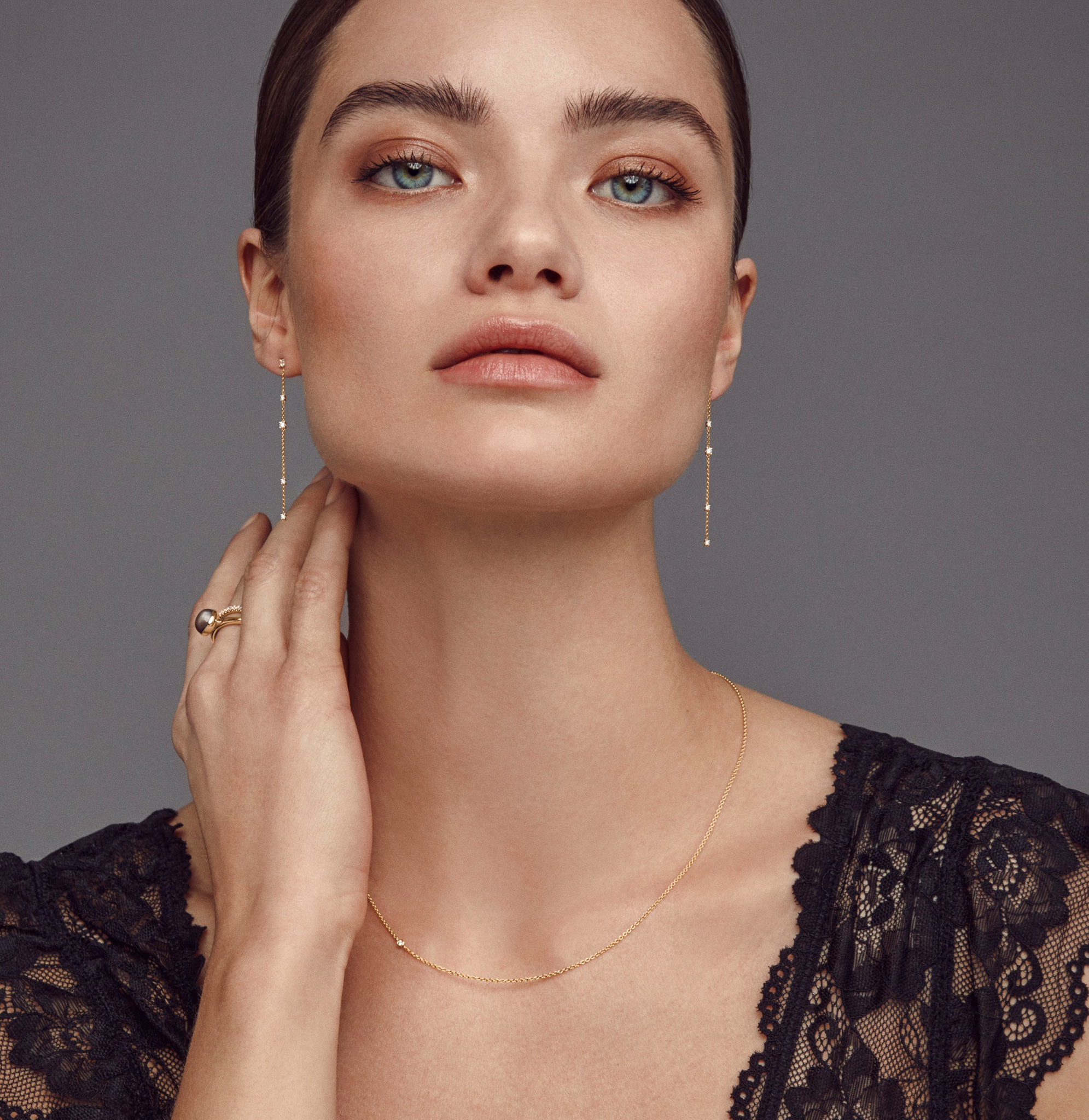 Model iført en tynd guldhalskæde fra Julie Sandlau med en synlig diamant nær kravebenet, samt øreringe og ring der ikke er en del af dette produkt